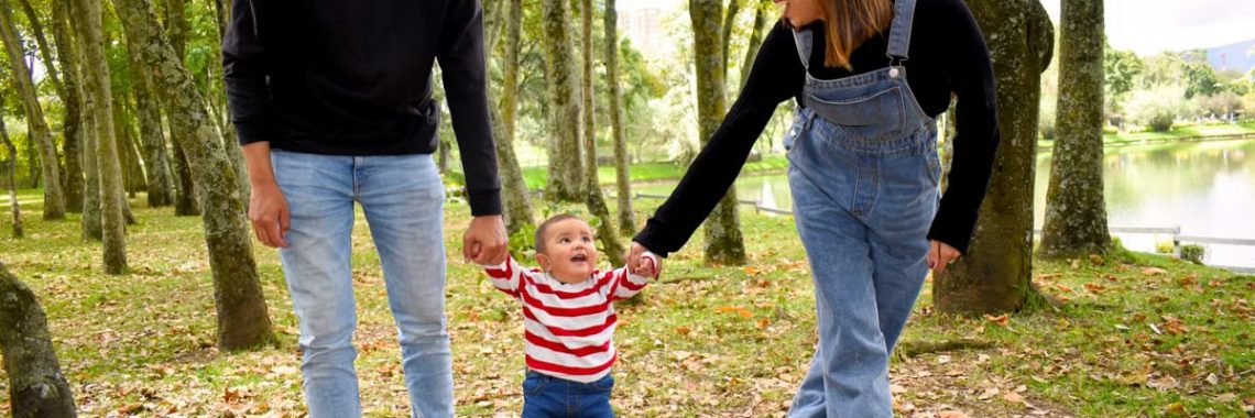 A joyful family enjoys a walk under lush green trees in the park.